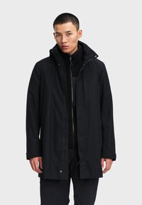 Cappotto impermeabile nero con colletto alto, zip frontale e bottoni automatici. Presenta un rivestimento interno testurizzato e maniche lunghe.