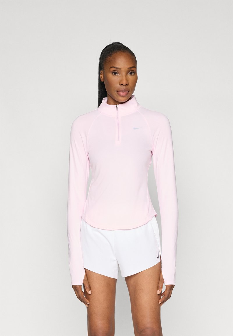 Bluză lungă cu mânecă din materiale fine, de culoare roz pal, cu guler cu fermoar și mâneci raglan. Design simplu cu un mic logo Nike pe piept.