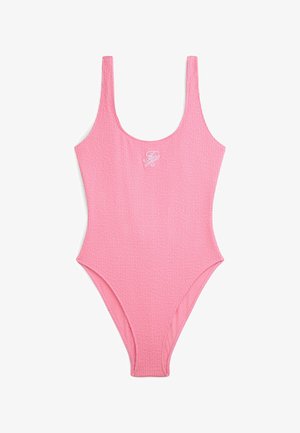 Pink tekstureret badedragt i ét stykke med rund halsudskæring og hvide broderede initialer på brystet, lagt fladt på hvid baggrund.