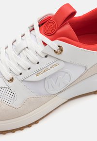 Adidași albi cu accente roșii, din materiale din suede și sintetice, cu detalii perforate, accesorii aurii și logo embosat.
