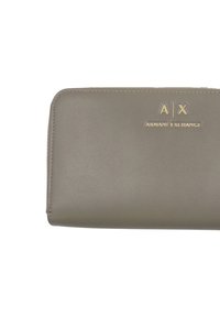 Portafoglio in pelle grigia con una texture liscia e loghi dorati "A|X" e "ARMANI EXCHANGE" impressi sul davanti. Chiusura con zip lungo il bordo.