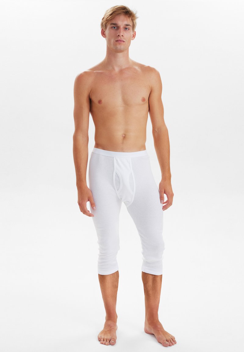White cotton fitted leggings with a mid-calf length, elastic waistband, and a front pouch detail; smooth texture and lightweight design.