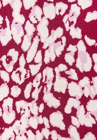 Roter Stoff mit einem weißen und hellrosa abstrakten Leopardenmuster, das unregelmäßige Formen und eine strukturierte Oberfläche aufweist.