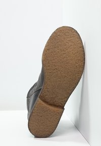 Chaussure grise avec une semelle en caoutchouc texturé. Matériau supérieur lisse, design discret et logo embossé sur la semelle.