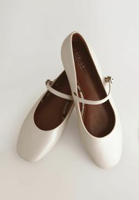 Vaaleanbeige ballet-kengät, joissa on sileä pinta, pyöreä kärki ja kapea nilkkahihna. Mukana pehmustettu pohja ja tasapohja.