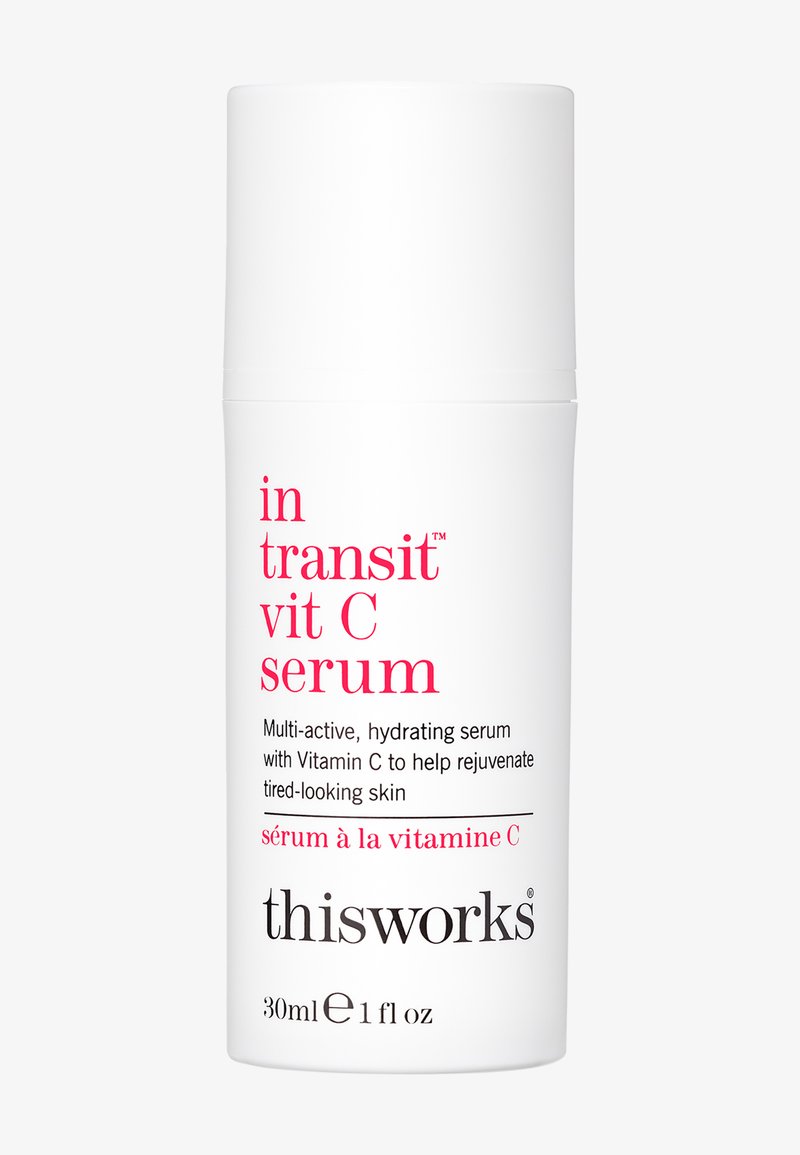 Weiße zylindrische Flasche mit Pumpenoberteil, beschriftet mit "In Transit Vit C Serum" in pinkem Text. Enthält 30 ml des feuchtigkeitsspendenden Serums.