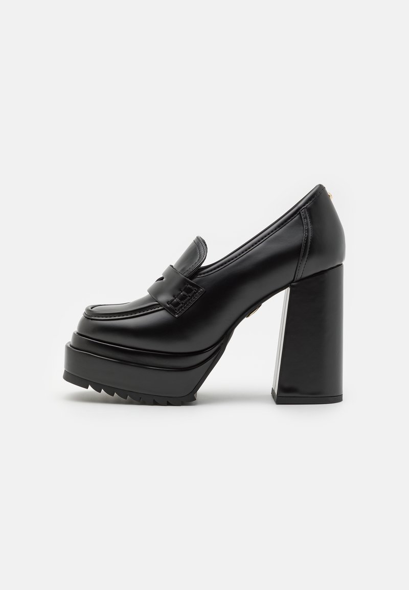 Chaussure plate-forme en cuir noir avec talon bloc épais et dessus style mocassin sur fond uni.