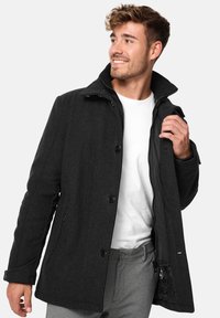 Abrigo de mezcla de lana gris con cuello alto, dos bolsillos frontales y un bolsillo interior con cremallera. Cierre de botón y textura suave.