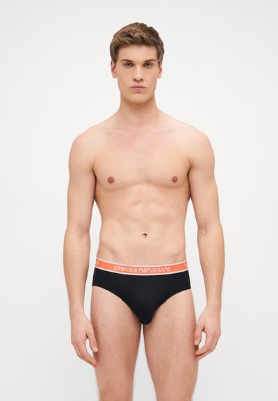 Slip neri da uomo con una larga fascia in bianco e arancione "Emporio Armani", che mettono in mostra una texture liscia e una vestibilità aderente.