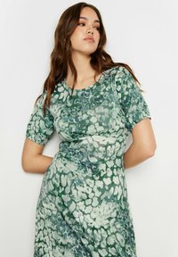 Grünes Blumenkleid aus weichem Stoff. Kurze Puffärmel, runder Ausschnitt und gerafftes Taillendetail. Verfügt über ein Farbverlaufsmuster in verschiedenen Grüntönen.