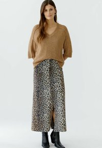 Brauner, kurzärmeliger, V-Ausschnitt Strickpullover, kombiniert mit einem Leopardenmuster, knöchellangen Rock mit einem seitlichen Schlitz. Schwarze Stiefeletten.