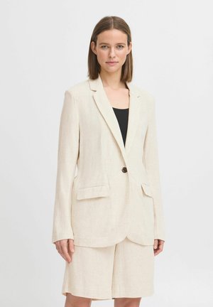 Světle béžový lněný blazer s klopami, zapínáním na jeden knoflík a předními kapsami, v kombinaci s odpovídajícími šortkami. Hladký povrch.