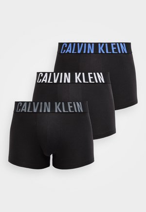 Trzy pary czarnych bokserek z elastycznymi paskami w talii, na których w kontrastowych kolorach: niebieskim, białym i szarym, widnieje napis "CALVIN KLEIN".