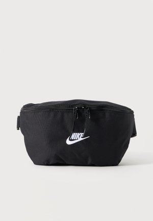 Μαύρο τσαντάκι μέσης Nike με δύο φερμουάρ και λευκό λογότυπο Nike μπροστά, απεικονισμένο σε απλό φωτεινό φόντο.