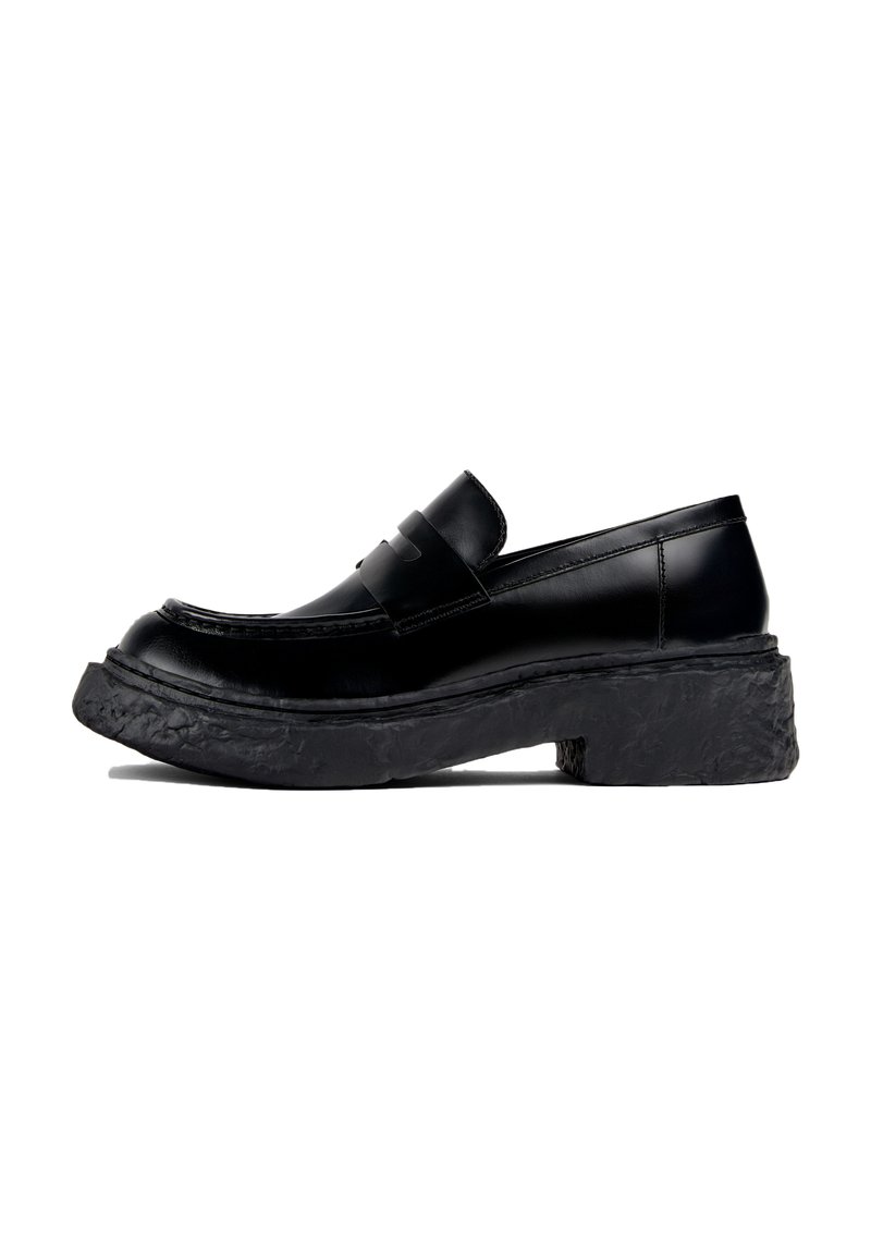 Schwarze Loafer aus glattem Leder, mit runder Zehenpartie und einer dicken, strukturierten schwarzen Plateausohle. Saubere Linien mit minimalen Akzenten.