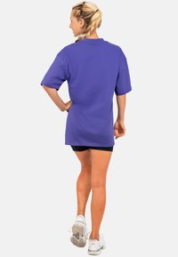 Paarse oversized t-shirt met korte mouwen, van katoen, met een ronde hals en een relaxte pasvorm, gecombineerd met zwarte shorts.