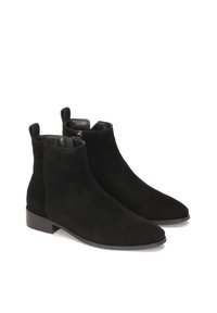 Botines de ante negro con una textura suave, punta afilada y tacón bajo. Presentan lengüetas en la parte posterior para facilitar su colocación.