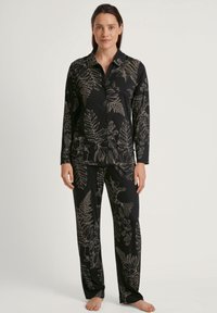 Zwart pyjama set met een lange mouw knoopsluiting shirt en bijpassende broek, voorzien van een subtiele bloemen- en varenprint in metallic zilveren tinten.