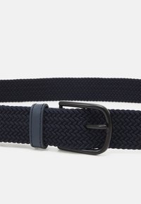 Cinturón tejido en navy con un tejido texturizado y una hebilla de metal negro mate. Presenta un detalle en cuero de contraste cerca de la hebilla para mayor detalle.