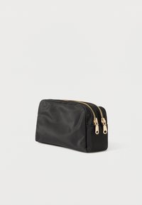 Mustast nailonist kotike struktureeritud disainiga. Omab kahte kuldset luku ja sujuva tekstuuriga. Kompaktne ja mitmekülgne hoiustamiseks.