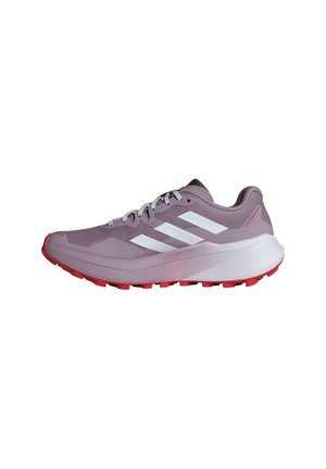 Chaussure de sport violette avec des rayures blanches, des détails rouges, une semelle épaisse et un relief rouge, présentée de côté sur un fond blanc.