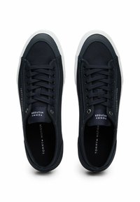 Zapatillas de lona azul marino con suelas de goma blanca, puntera redonda y diseño clásico de cordones. Presentan un logo en la lengüeta y detalles de costura.
