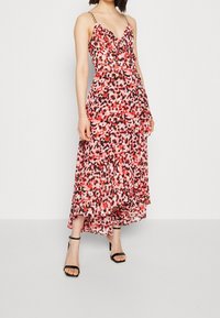 Maxiklänning i en rosa och svart blommig print, med volangdetaljer, spaghettiband och en flödande kjol med en vågig nederkant.