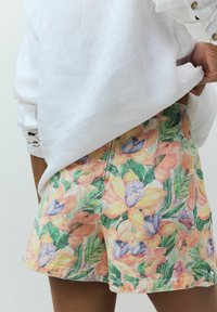 Blommiga shorts med en flerfärgad design med gula, orangea och lila blommor mot en grön bakgrund, tillverkade av lättviktsmaterial.