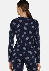 Marinblus med långa ärmar och ljusgråa prickar. Tillverkad av mjukt tyg med rundad halsringning och sömmar på sidorna för en figurnära look.