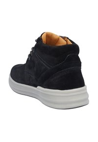 Zapato alto de ante negro con suela de goma crema. Presenta costuras tonales, cordones en la parte frontal y un forro interior en tono marrón. Sin marcas visibles.