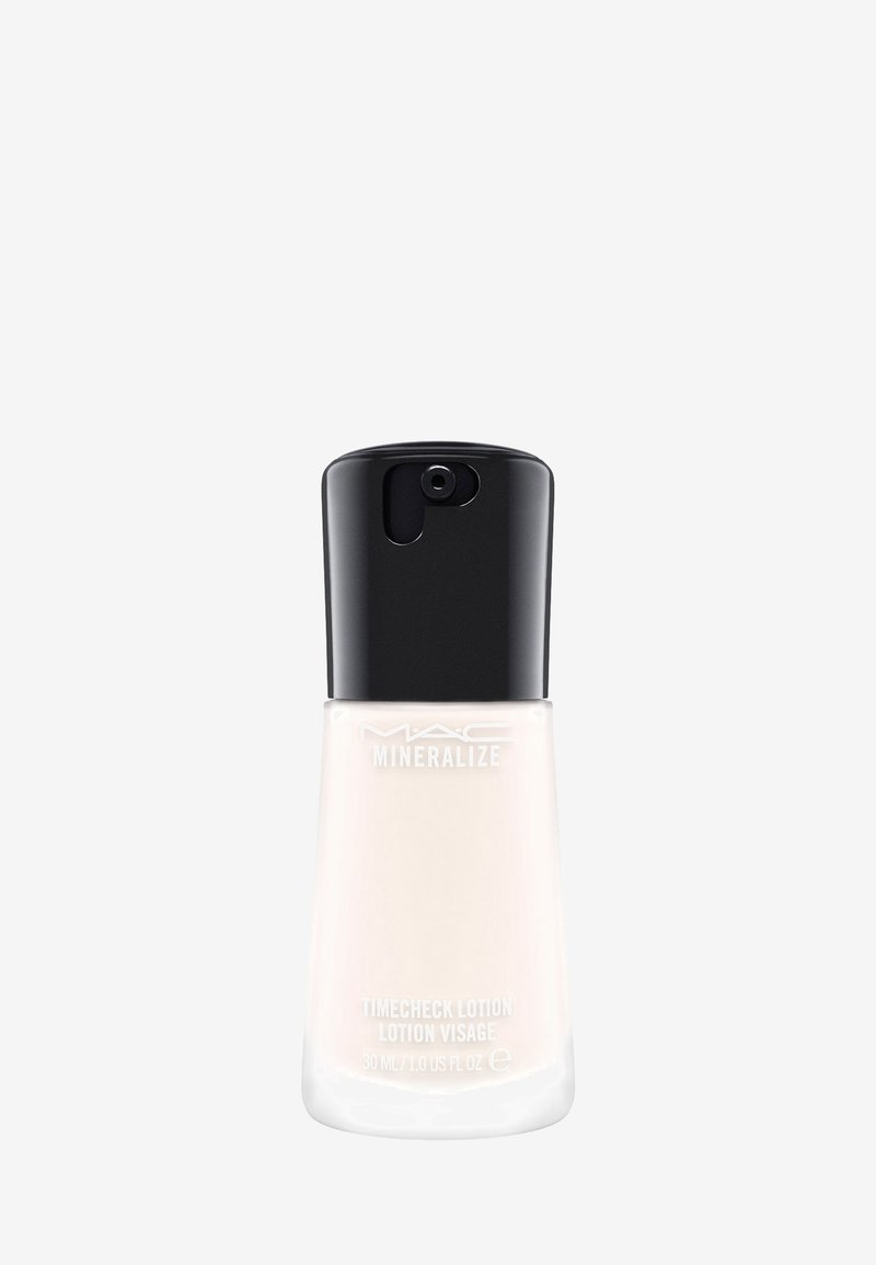 Lotion MAC Mineralize Timecheck in una bottiglia di vetro trasparente con una base piatta, tappo nero e testo bianco. Texture liscia, consistenza liquida.