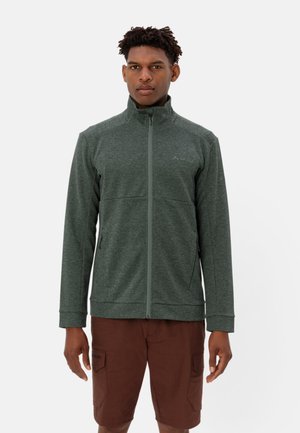 Fleecejack in donkergroen, met een ritssluiting aan de voorkant en een hoge kraag. Heeft een gestructureerde stof en twee zijzakken. Draagt met bruine shorts.