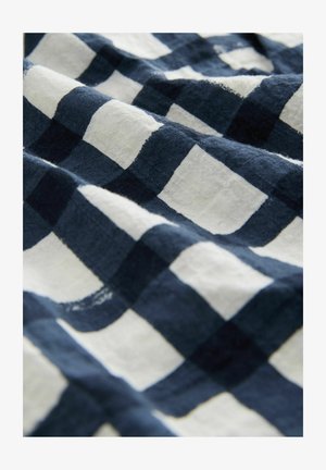 Kariertes Stoff mit abwechselnd navyblauen und weißen Quadraten, das eine weiche Textur und ein leicht zerknittertes Aussehen zeigt.