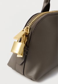 Γκρίζα δερμάτινη τσάντα χειρός με χρυσό φερμουάρ και διακοσμητικ�ή κλειδαριά. Διαθέτει δομημένο σχήμα και λείο υλικό, τονίζοντας τις λεπτομέρειες της μάρκας.