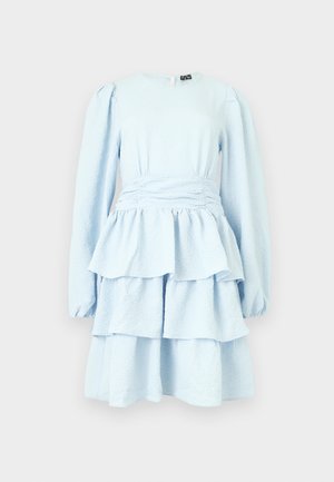 Vaaleansininen pitkähihaisen mekon teksturoidulla kankaalla, istuvalla vyötäröllä ja kerroksellisilla röyhelöhameen kerroksilla yksiväristä taustaa vasten.