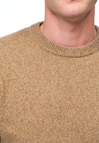 Bruine gebreide trui met een ronde halslijn. De stof heeft een gestructureerd patroon en een zachte, warme uitstraling.