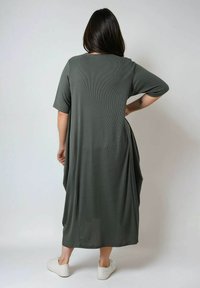 Olijfgroene, geribbelde maxi jurk met korte mouwen en een losse pasvorm, met zijzakken en een ronde halslijn. Gekaapt met witte sneakers.