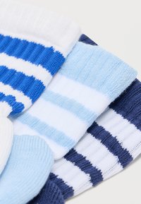 Set de șase șosete tricotate în nuanțe variate de albastru și alb. Caracteristici includ dungi și textură tip ripă. Designuri și modele variate.