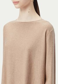 Beige tröja med mjuk textur, något oversized passform och bred halsringning. Kompositionen verkar vara av fint stickat material.