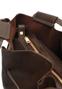 Rudos odos rankinės vidus, kur matyti kišenė su užtrauktuku ir auksinės spalvos detalėmis, minkšta pamušalas ir dvi nešimo rankenos.