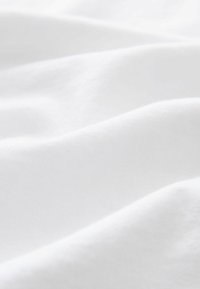 Tissu en coton blanc avec une texture lisse, affichant de douces vagues et de subtiles variations de lumière et d'ombre. Idéal pour les vêtements et les textiles d'intérieur.