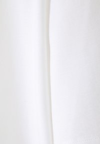 Gros plan sur un tissu blanc propre avec une texture douce et une couture visible courant verticalement au centre.