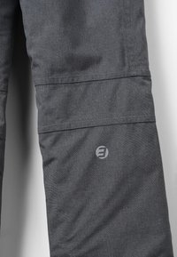 Graue Hose aus strukturiertem Stoff, mit einer horizontalen Naht und einem kreisförmigen Logo in einem helleren Farbton am unteren Bein.
