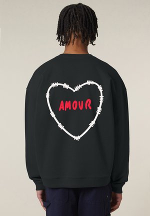 Zwarte sweatshirt met een losse pasvorm. Heeft een hartontwerp van witte prikkeldraad en het woord "AMOUR" in rode letters op de achterkant.