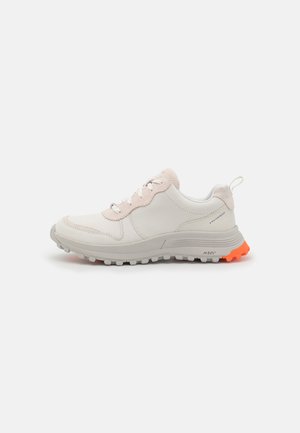 Baskets légères en cuir crème et rose pâle, dotées d'un design texturé, d'une semelle grise et de accents orange vif au niveau du talon.