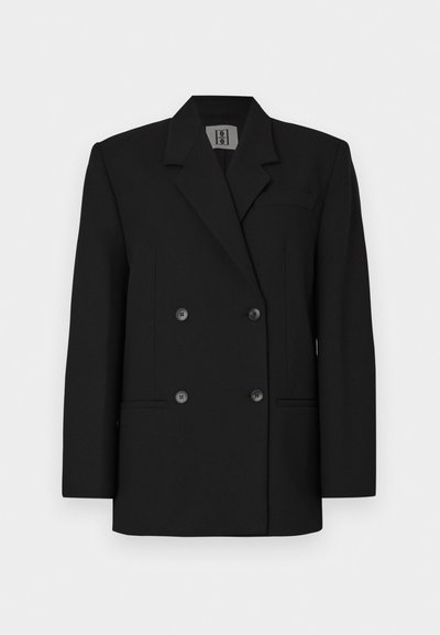 Blazer preto de duas fileiras de botões, design ajustado, ombros estruturados, bolsos na frente, feito de tecido texturizado, com grandes botões pretos.