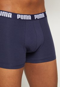 Navy blue boxer brief made of soft fabric with a white Puma logo on the elastic waistband and a fitted design. Features flat seams.