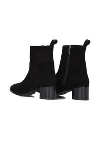 Een paar zwarte nubuck enkellaarsjes met een rits aan de zijkant, trekbandjes en blokhakken op een witte achtergrond.