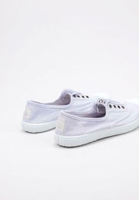 Scarpe slip-on di tela viola chiaro con suole in gomma bianche, caratterizzate da piccoli occhielli metallico e un'etichetta con logo sul tallone.