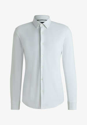 Camicia bianca a maniche lunghe con bottoni, realizzata in tessuto testurizzato, con colletto a punta e orlo dritto. Presenta bottoni standard sulla parte anteriore.